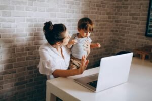 Maman entrepreneuse travaillant sur son ordinateur pendant que son enfant joue à côté dans le salon