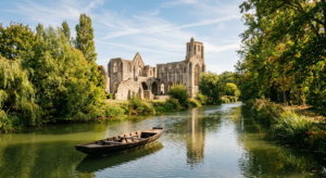 Vue panoramique des ruines majestueuses de l'Abbaye de Maillezais bordant les canaux paisibles du Marais Poitevin sous une lumière de fin d'après-midi.