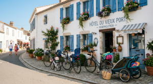 Façade lumineuse de l'Hôtel La Chaize à Noirmoutier avec des vélos de location à l'entrée et une ambiance de vacances en famille sous le soleil.
