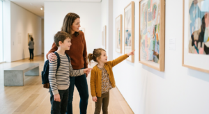 Une mère et ses deux enfants observent avec curiosité les œuvres exposées dans un musée lumineux et moderne, ambiance chaleureuse et familiale.