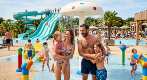 Une famille avec de jeunes enfants s'amusant dans une zone de jeux aquatiques colorée et sécurisée dans un parc aquatique ensoleillé en Vendée.