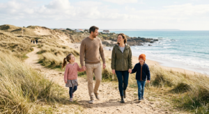 Une famille avec deux enfants se promène sur un chemin côtier sauvage en Vendée lors d'une journée ensoleillée de printemps, avec l'océan Atlantique en arrière-plan.