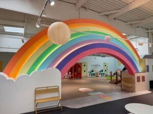 Vue chaleureuse d'un espace de jeu d'imitation en bois dans un parc indoor lumineux à Nîmes, style ludo-éducatif.