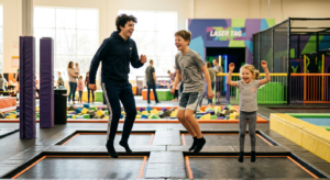 Un groupe d'adolescents et d'enfants en train de s'amuser sur des trampolines géants dans un complexe de loisirs moderne et lumineux.